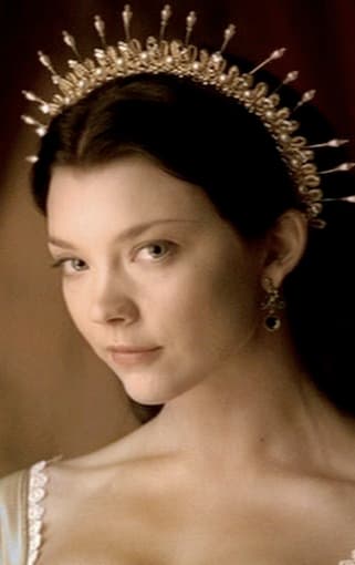 A close-up portrait of a woman with dark hair wearing an ornate, jeweled crown and a matching earring, looking directly at the camera with a neutral expression.