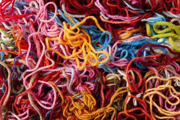 A close-up photograph of a tangled pile of colorful yarn in various shades of red, pink, orange, blue, and green. The image is used as a visual metaphor for the overwhelming and chaotic nature of Twitter, as referenced in the accompanying text.