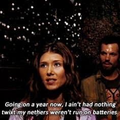 A screenshot of a movie scene featuring a woman in the foreground and a man in the background, set against a dark, outdoor backdrop with bokeh lights. A caption is overlaid at the bottom of the image.