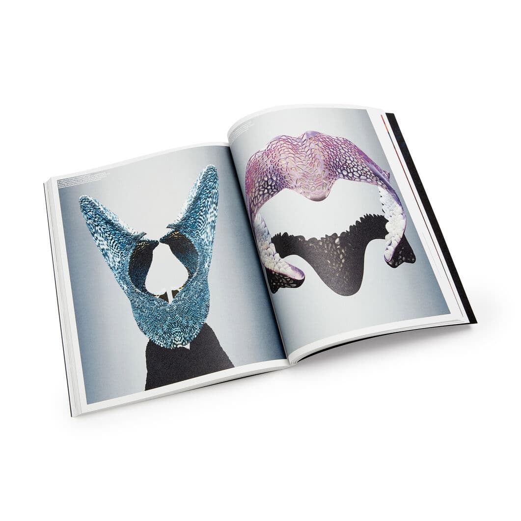 An open book displaying two pages of abstract, 3D-rendered organic structures. The left page features a blue, lattice-like form, while the right page shows a similar structure in purple and black.