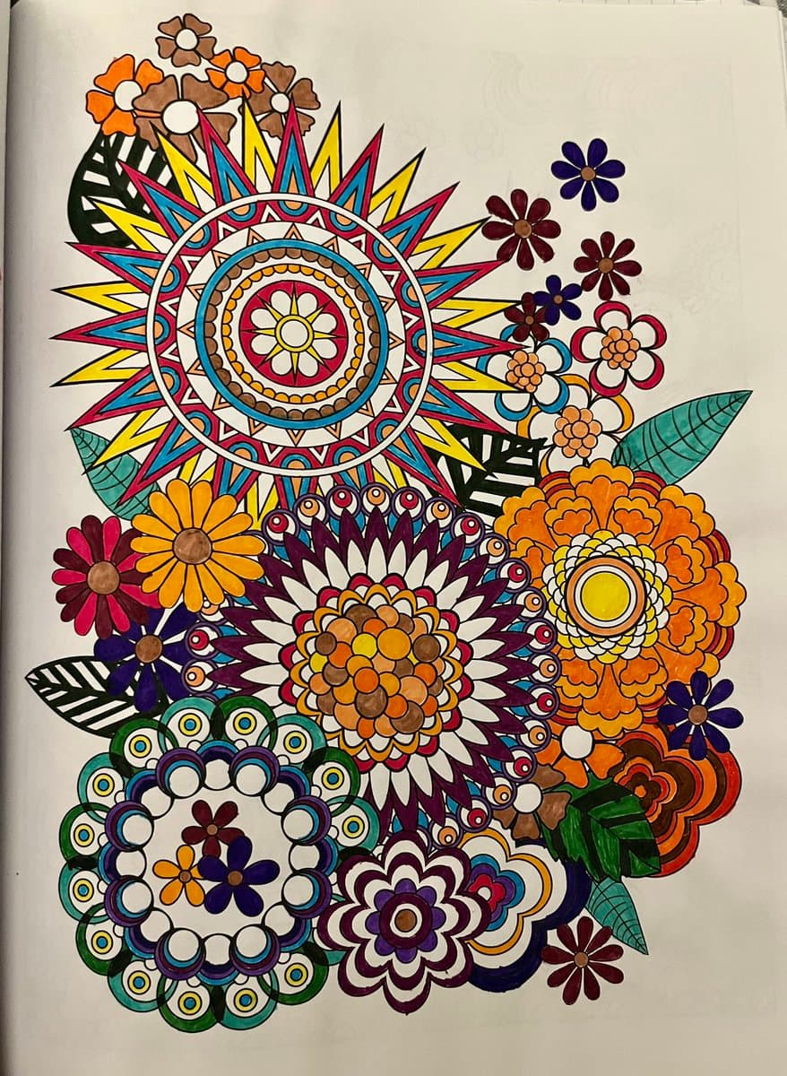 A completed page from a coloring book featuring a vibrant, intricate design of a sun and various flowers in bright colors of orange, yellow, red, blue, and purple. The artwork is filled in with markers or colored pencils, showcasing a detailed and cheerful illustration.