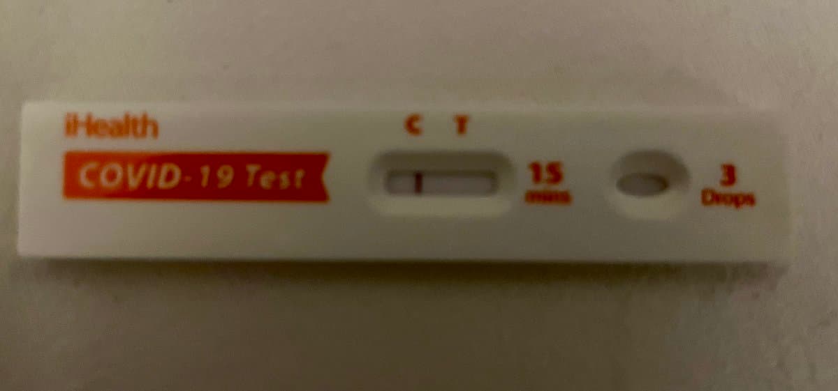 A close-up photograph of a used iHealth COVID-19 rapid antigen test cassette. The test window shows a single line in the control (C) position, indicating a negative result.