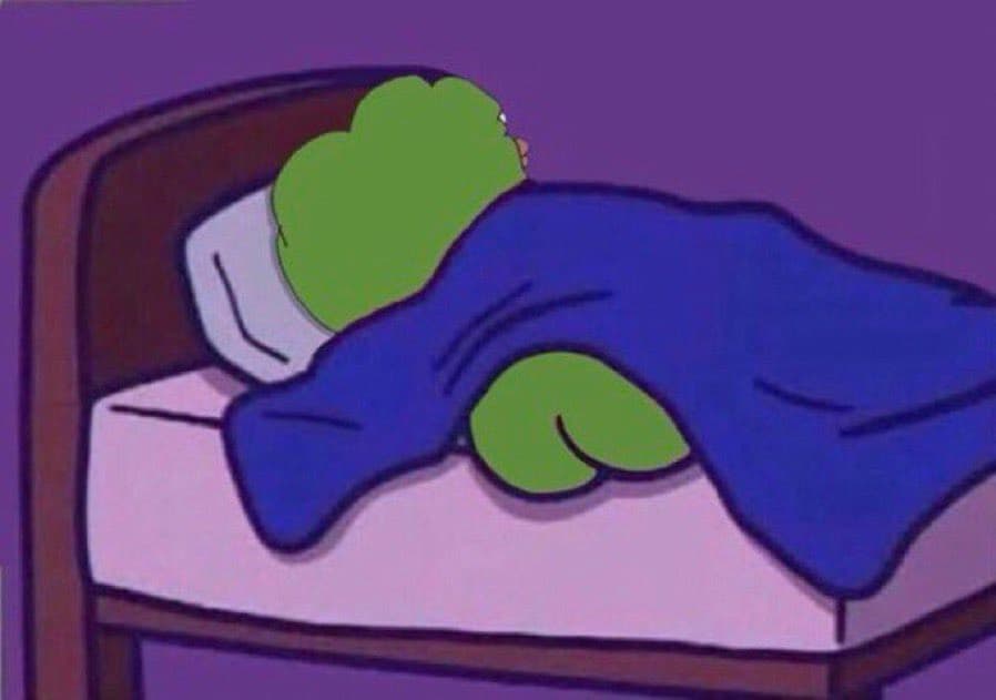 A still from an animated cartoon showing a green character sleeping in a bed with a blue blanket. The character is lying on their side on a white pillow against a purple background.