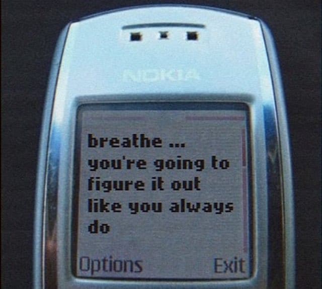 A close-up photograph of a silver Nokia mobile phone displaying a text message on its screen. The message reads: "breathe ... you're going to figure it out like you always do".