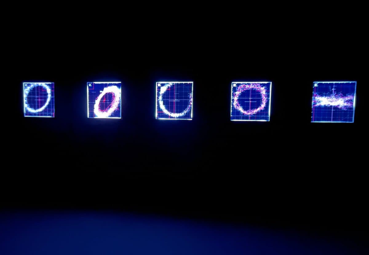 A row of five illuminated square panels displaying abstract, glowing circular and linear patterns against a dark background, likely part of an art installation.