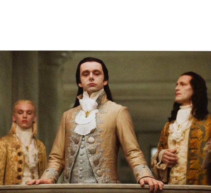 A still from the film 'The Young Victoria' showing three men in 19th-century formal attire standing on a balcony. The central figure, played by Rupert Friend, looks down with a smug expression, while the two men on either side look on with similar expressions of disdain or superiority.