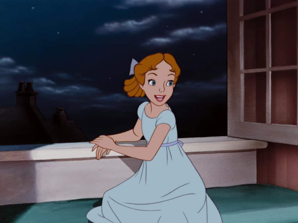 A still from a classic 2D animated film showing a young woman with red hair and a white bow sitting on a window ledge at night. She is wearing a light blue nightgown and looking out at a dark, starry sky with rooftops in the distance.