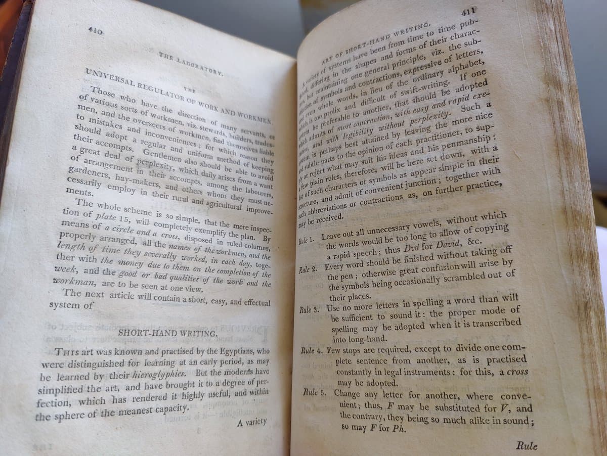 A photograph of an open 18th-century book displaying two pages of text. The left page is titled "THE LABORATORY" and contains a section on "SHORT-HAND WRITING," while the right page, titled "ART OF SHORT-HAND WRITING," lists five rules for the system.