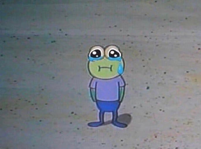 A screenshot of a cartoon frog character with a sad expression, tears in its eyes, and a single tear rolling down its cheek. The character is wearing a purple shirt and blue shorts, standing against a plain, speckled background.