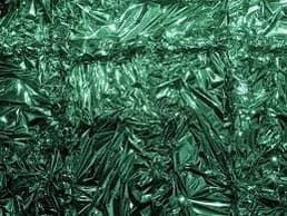 A close-up photograph of crumpled, reflective green material, likely foil or plastic, with a textured, faceted surface.