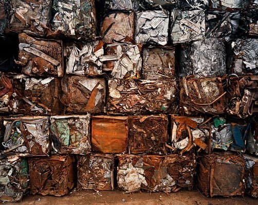 A stack of compressed bales of mixed scrap metal, including aluminum and copper, arranged in a grid pattern.