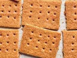A close-up photograph of several square graham crackers arranged on a light-colored surface.