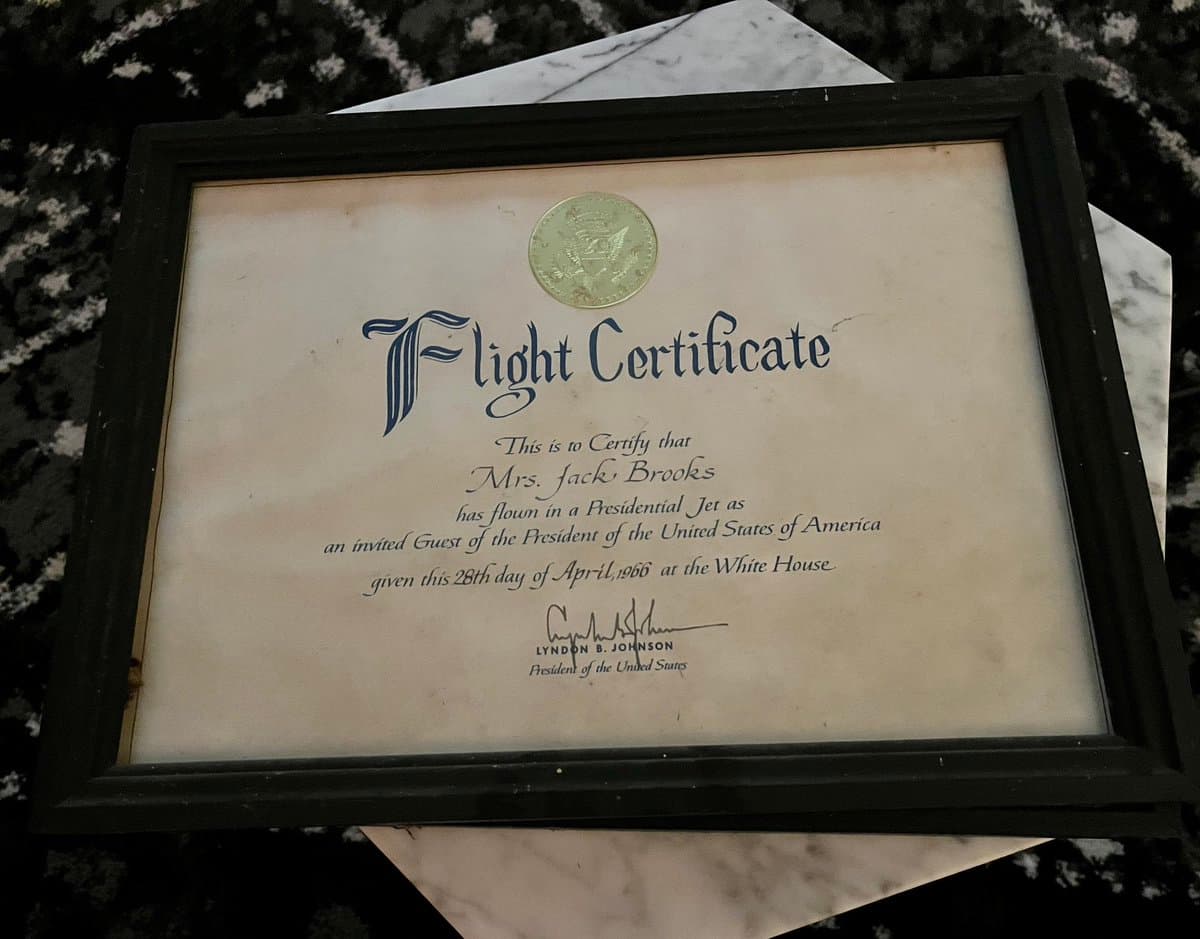 A framed flight certificate resting on a marble surface. The document, bearing the seal of the President of the United States, certifies that Mrs. Jack Brooks flew on a Presidential Jet as an invited guest of the President on April 28, 1966, and is signed by Lyndon B. Johnson.