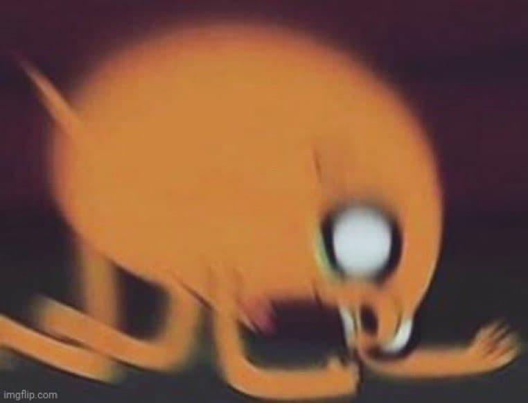 A low-resolution, blurry image of an orange cartoon character with a large white eye, appearing to be in a state of distress or falling. The image has a dark background and a watermark in the bottom left corner.