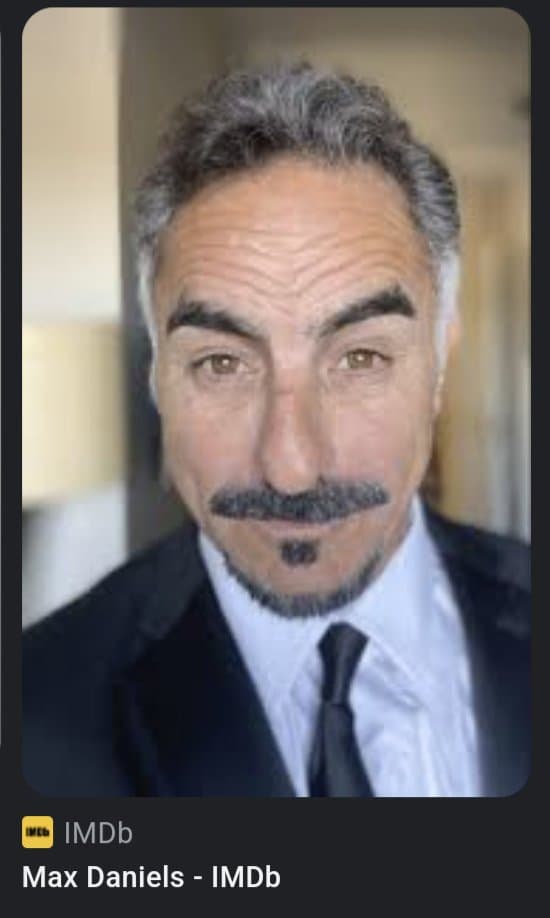 A screenshot of an IMDb profile page featuring a headshot of a man with gray hair and a mustache wearing a suit and tie. Below the photo, the IMDb logo and the name 'Max Daniels - IMDb' are displayed.