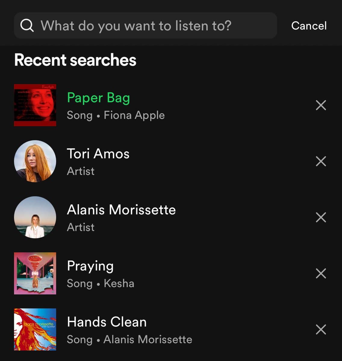 A screenshot of the Spotify mobile app's search screen, showing a list of recent searches. The list includes the songs 'Paper Bag' by Fiona Apple and 'Praying' by Kesha, and the artists Tori Amos and Alanis Morissette.