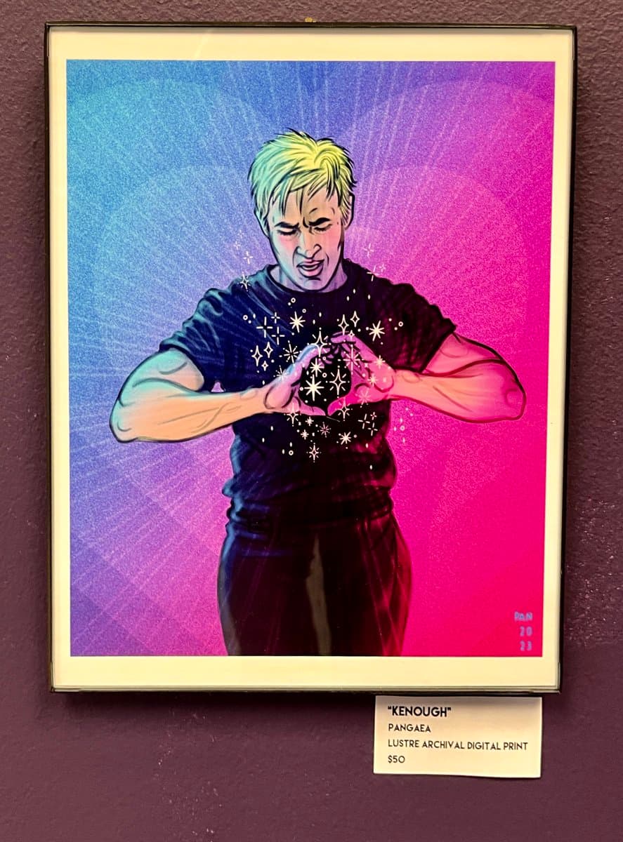 A framed digital art print depicting a person with short blonde hair making a heart shape with their hands, surrounded by sparkling stars, against a vibrant blue and pink gradient background. A small label below the frame identifies the piece as "KENOUGH" by Pangaea, a luster archival digital print priced at $50.