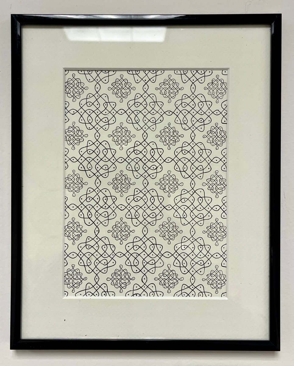 A framed piece of black-and-white line art featuring a repeating geometric pattern of interlocking knots and loops. The artwork is mounted on a white mat within a simple black frame, hanging on a light-colored wall.