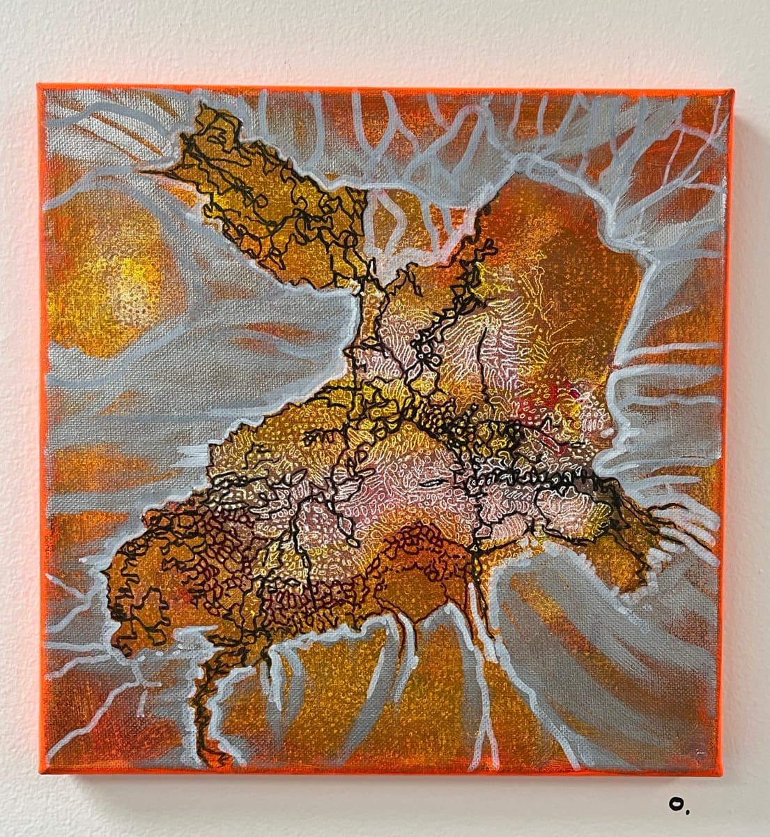 A square canvas painting depicting an abstract, map-like landscape in warm earth tones of orange, brown, and gold, with intricate black line work and white, vein-like patterns. The artwork is mounted on a plain white wall.