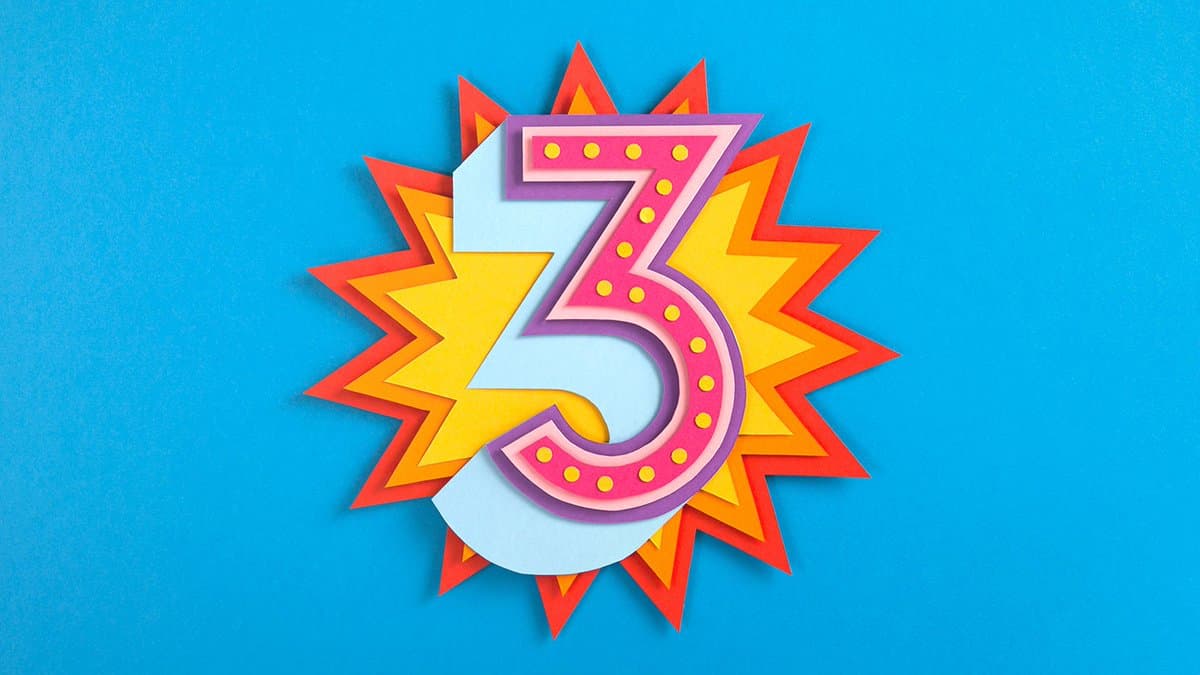 A colorful, paper-cutout style illustration of the number 3 set against a bright blue background. The number is pink with yellow dots and is surrounded by a jagged, starburst shape in shades of red, orange, and yellow.