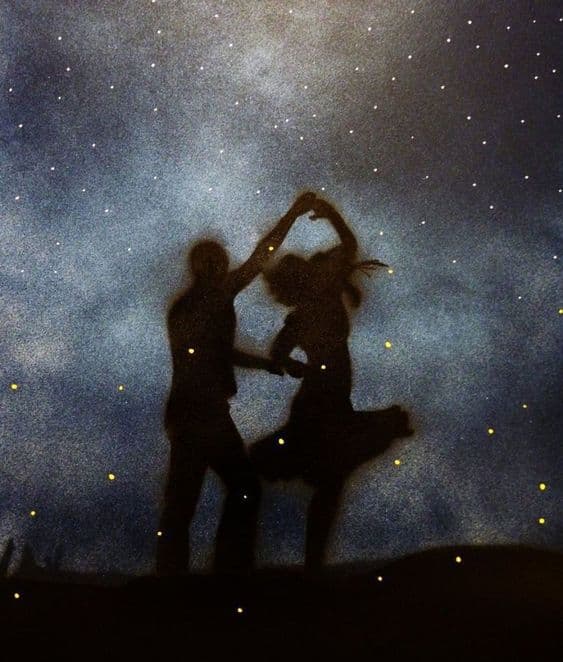 A silhouette of a couple dancing against a starry night sky, with small lights scattered across the scene.