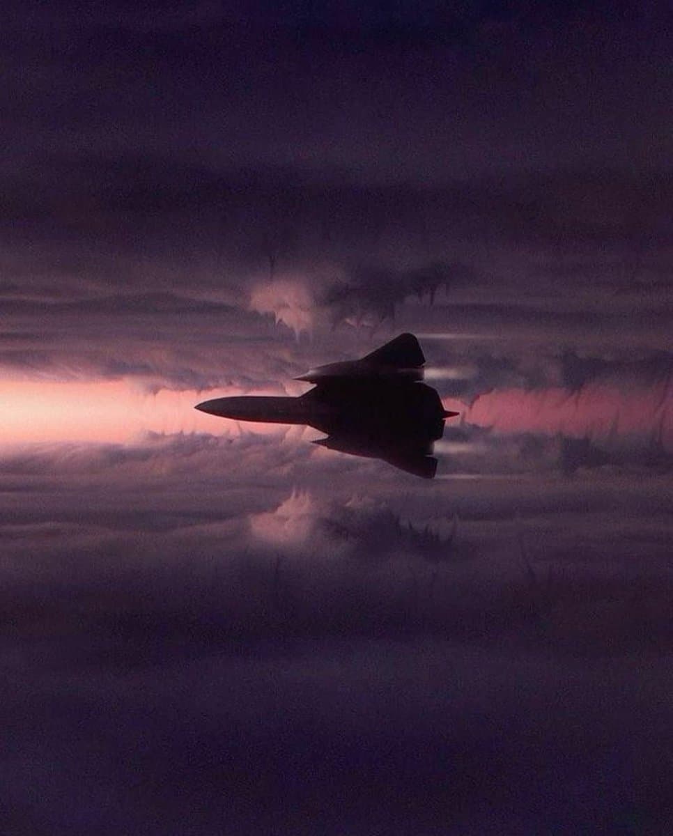 A digital illustration of a stealth fighter jet flying through a dark, cloudy sky at dusk or dawn. The aircraft is silhouetted against a horizon glowing with pink and purple light.