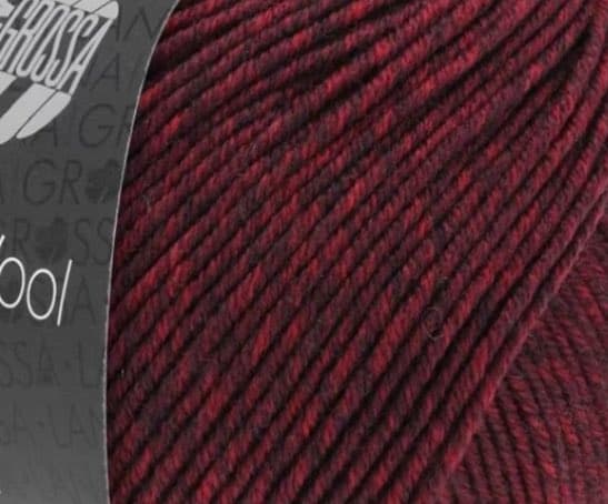 A close-up photograph of a skein of dark red and maroon variegated yarn with a partially visible label on the left side.