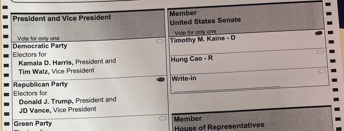 A close-up photograph of a paper ballot showing sections for voting for President and Vice President, and a United States Senate seat. The ballot lists candidates from the Democratic, Republican, and Green parties, as well as a write-in option.