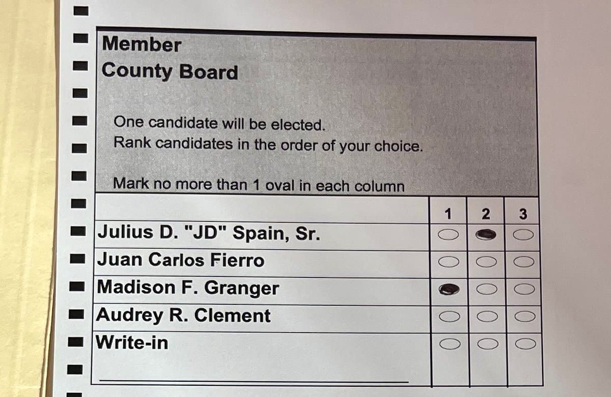 A close-up photograph of a paper ballot for a Member of the County Board election, showing a ranked-choice voting format. The ballot lists five candidates and a write-in option, with the first-choice oval filled in for Madison F. Granger and the second-choice oval filled in for Julius D. "JD" Spain, Sr.