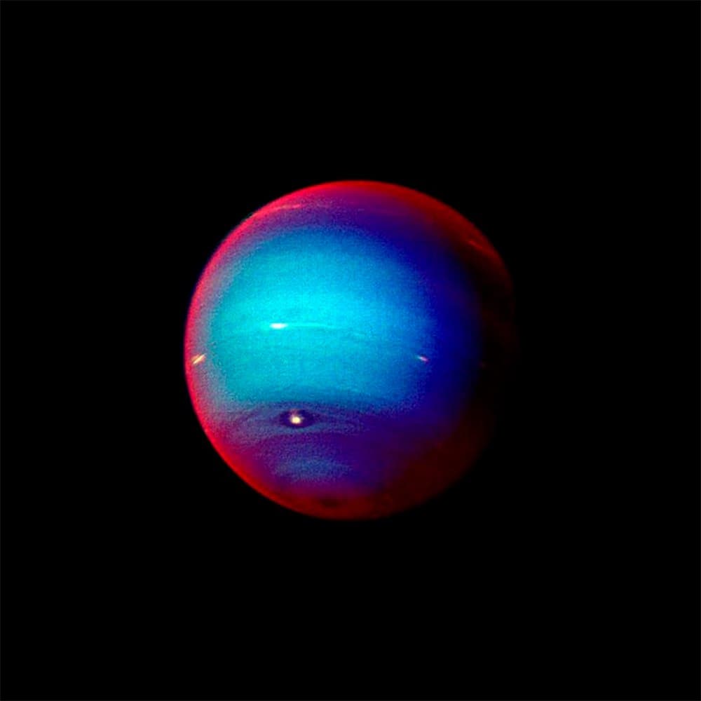 An enhanced color photograph of the planet Neptune set against a black background, featuring a bright blue center and a reddish-purple outer rim.