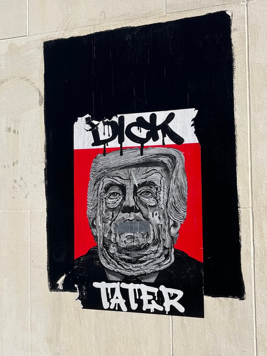 A photograph of a piece of street art or a poster on a wall featuring a stylized, black-and-white portrait of Donald Trump against a red and white background. The image is framed by a black border with the word "DICK" written in black graffiti-style letters at the top and "TATER" in white letters at the bottom.