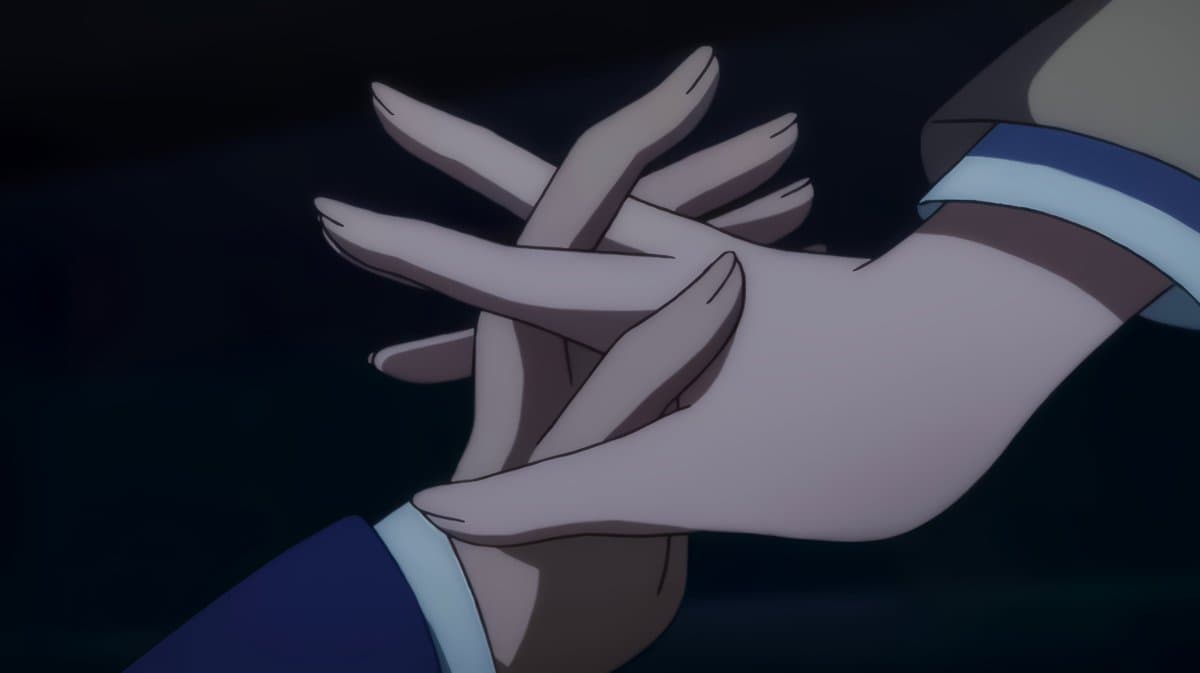 An anime-style illustration showing a close-up of two hands gently clasped together against a dark background. The image features characters wearing blue and white cuffs, conveying a sense of intimacy or connection.