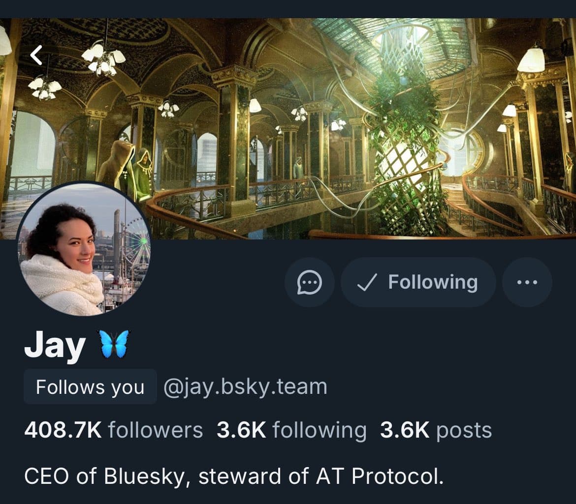 A screenshot of a Bluesky social media profile page. The profile header shows a stylized, ornate interior with a large, illuminated plant structure. The profile picture is a circular photo of a smiling woman in a white coat. The profile name is 'Jay' with a blue butterfly emoji, and the handle is '@jay.bsky.team'.
