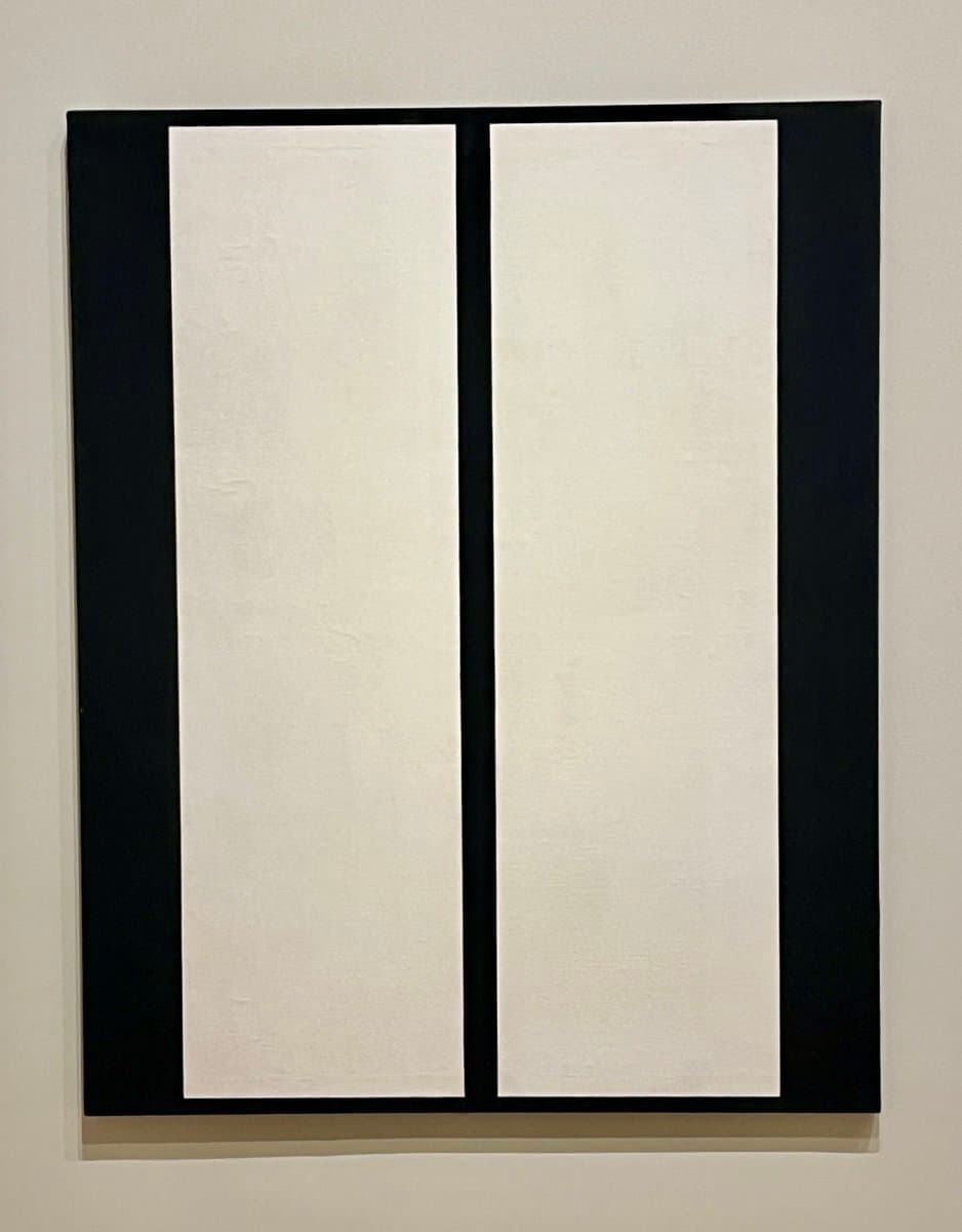 A minimalist abstract painting featuring two vertical white rectangles set against a black background, displayed on a light-colored wall. The composition emphasizes simple geometric forms and high contrast.