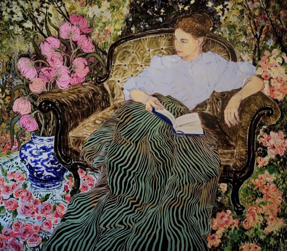 A painting depicting a woman with reddish-brown hair sitting in a tufted armchair, reading a book. She is surrounded by lush greenery and vibrant pink and red flowers, with a blue and white vase of pink flowers on a table beside her.