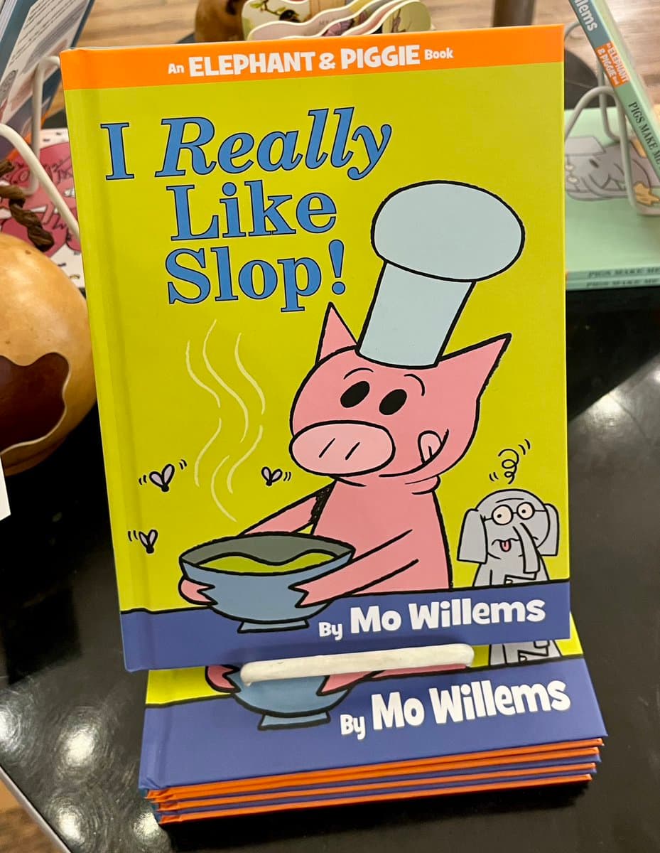 A stack of children's picture books titled 'I Really Like Slop!' by Mo Willems, featuring the character Piggie from the Elephant & Piggie series. The cover shows Piggie wearing a chef's hat and holding a steaming bowl of slop, with the character Gerald looking on.