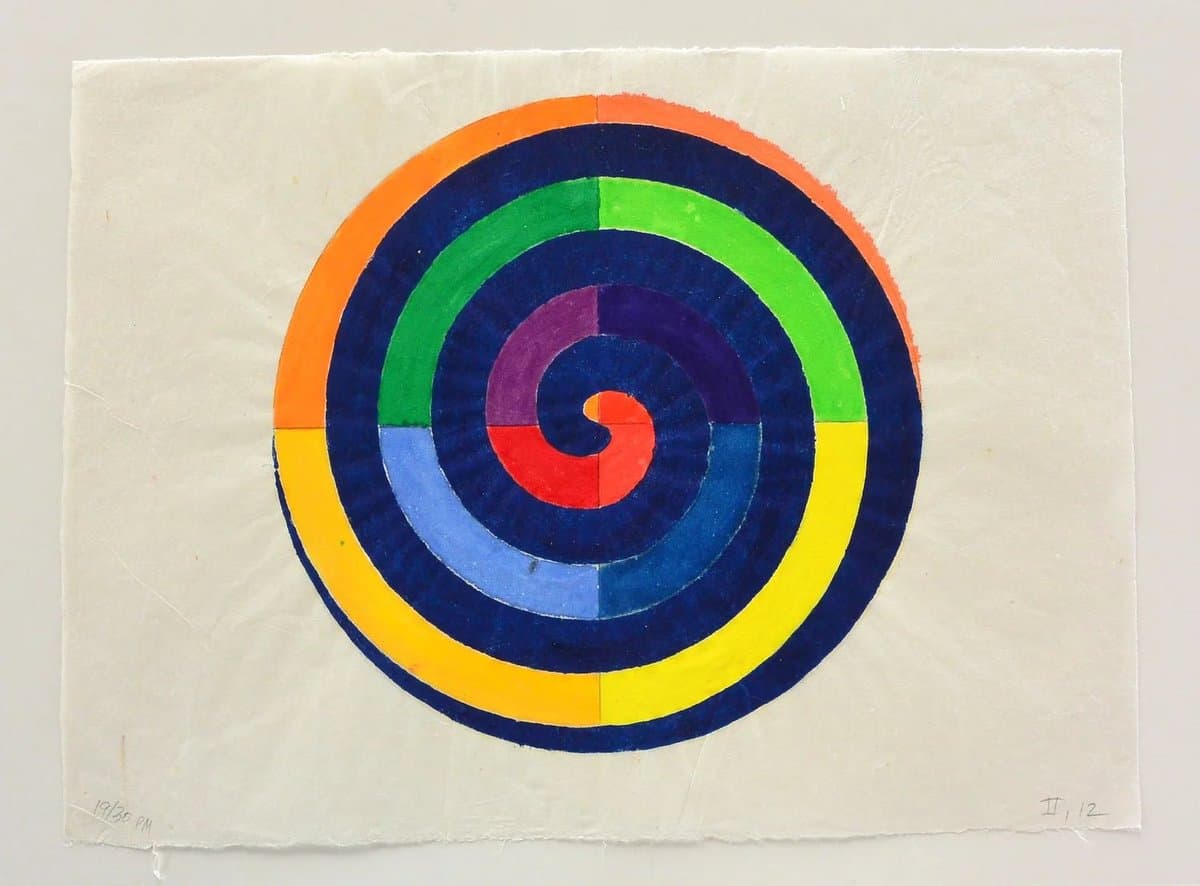 A woodblock print featuring a large, multi-colored spiral design on a white paper background. The artwork consists of concentric rings in orange, blue, green, yellow, purple, and red, with a small red spiral at the center.