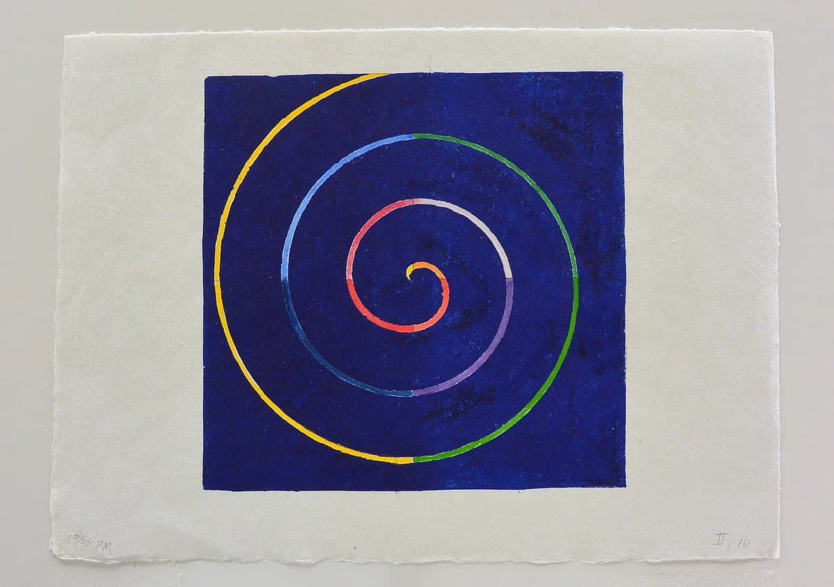 A woodblock print featuring a multicolored spiral on a dark blue square background, set within a white paper border. The print is signed and dated in the lower left corner and numbered in the lower right corner.