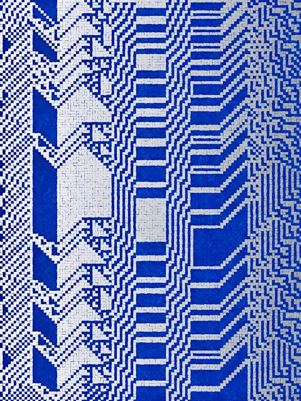 A close-up photograph of a blue and white ceramic tile mosaic featuring a geometric, pixelated pattern. The design consists of repeating angular shapes and lines that create a digital or retro-computing aesthetic.